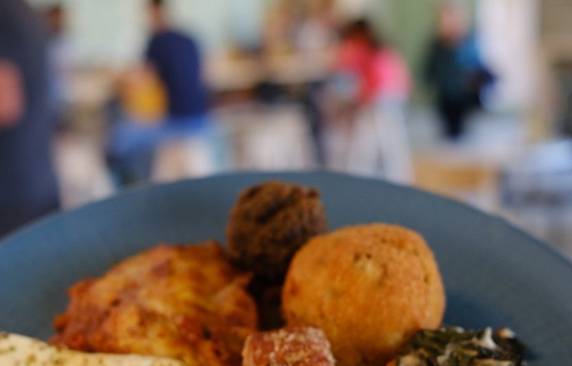 Photo d'une assiette sur laquelle est posé un falafel, avec en fond un caféteria.